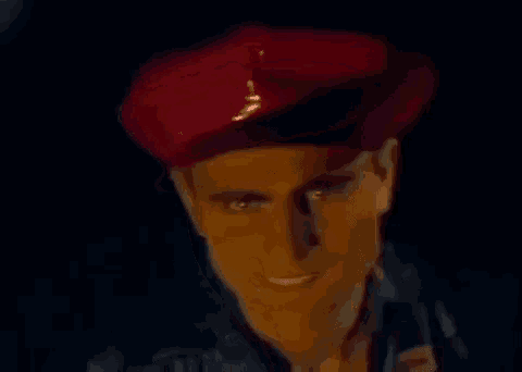 a close up of a man wearing a red beret and smiling .