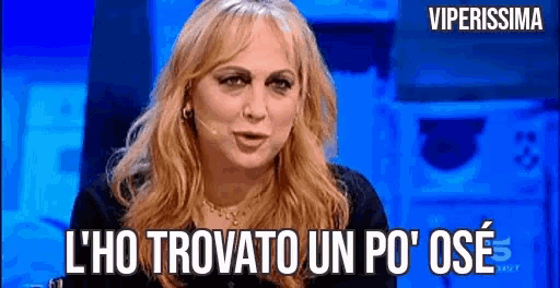 a woman with blonde hair is talking into a microphone and says l ' ho trovato un po ' ose .
