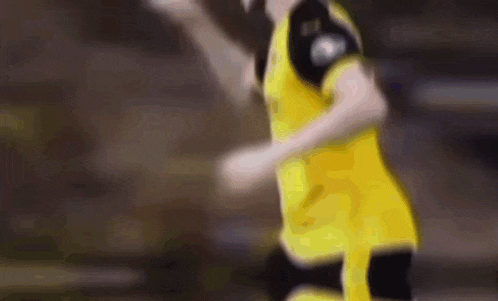 a blurred image of a soccer player wearing a yellow jersey