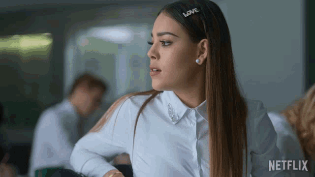 a woman wearing a white shirt has a hair clip that says love