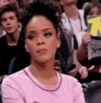 a woman in a pink sweater is sitting in a crowd of people .