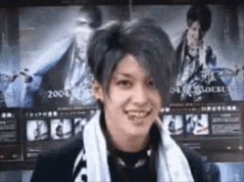 a young man with a towel around his neck is smiling in front of a poster of a man .