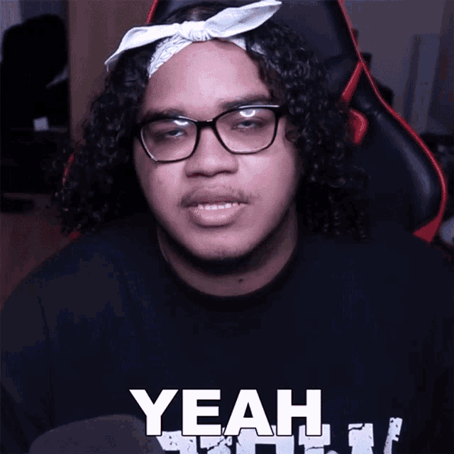 a man with curly hair wearing glasses and a bandana that says yeah