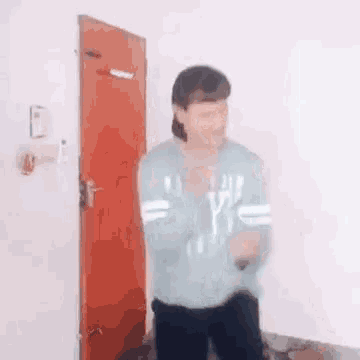 a man is standing in front of a red door and dancing .