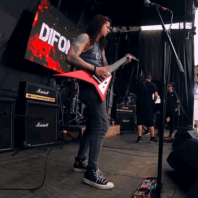 a man playing a red guitar in front of a screen that says difor