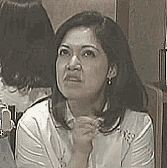 a woman is sitting in front of a mirror with her hands folded in front of her face .