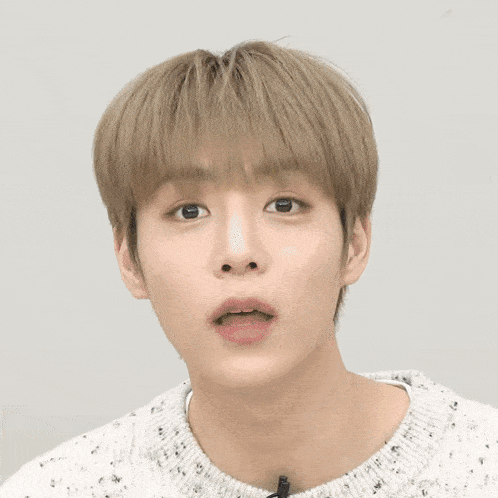a close up of a young man 's face with a sweater on