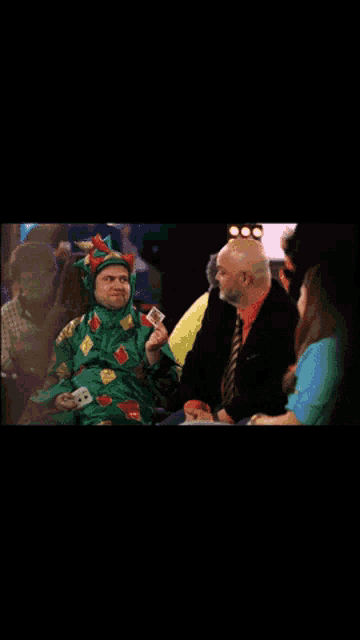 a man in a green sweater is sitting next to another man in a suit
