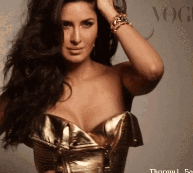 a woman with long hair is wearing a gold corset and bracelets