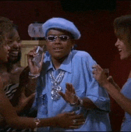 a man wearing sunglasses and a blue beret talks to two women