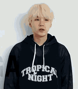 a young man with blonde hair is wearing a black hoodie and earrings .