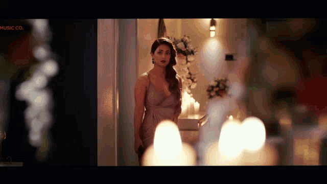 a woman in a dress is standing in a room with candles and the words music co. on the bottom right