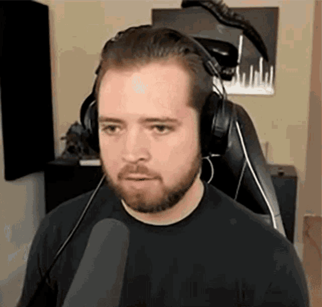 a man with a beard is wearing headphones and holding a microphone .