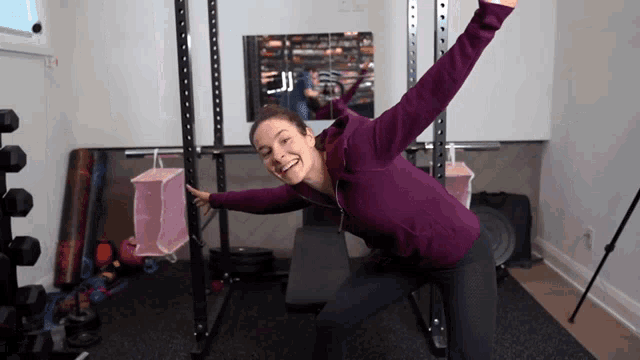 a woman in a purple sweatshirt is standing in front of a mirror