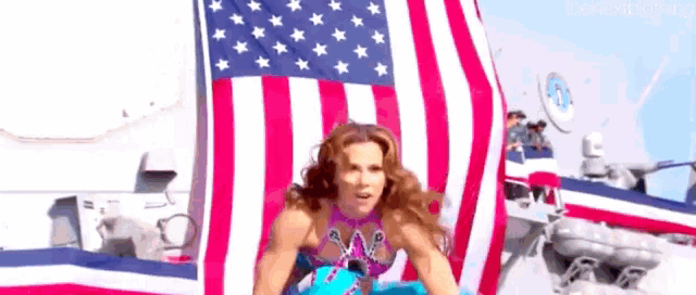 a woman in a bikini is standing in front of an american flag .