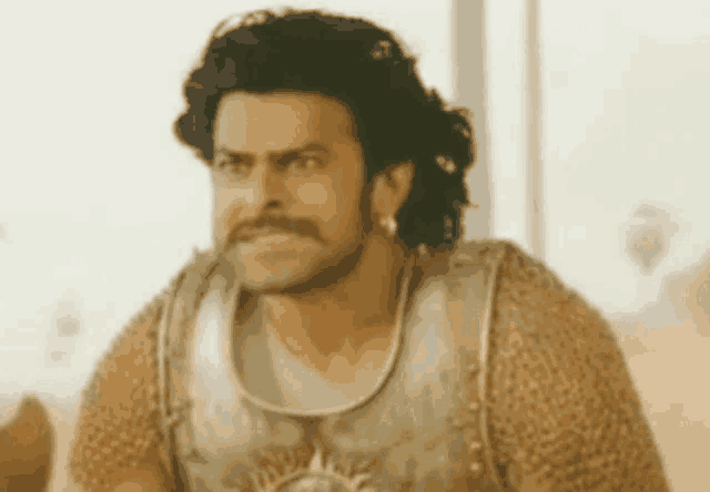 a man with a mustache and a beard is wearing a armored vest and earrings .