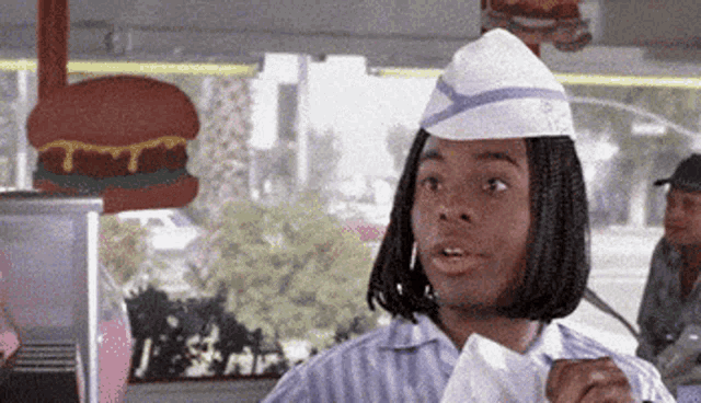 a man wearing a white hat and a striped shirt is standing in a diner .