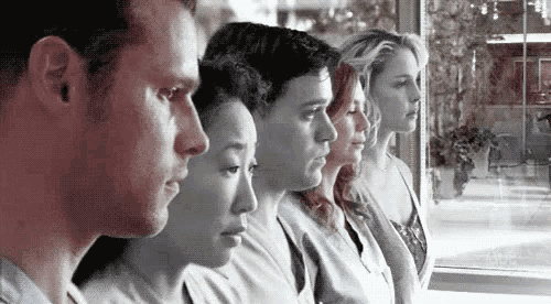 a group of people are standing next to each other in front of a window .