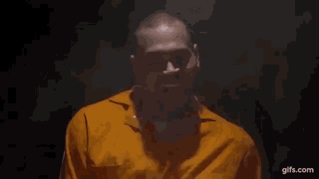 a man in an orange prison uniform is laughing and sticking his tongue out .