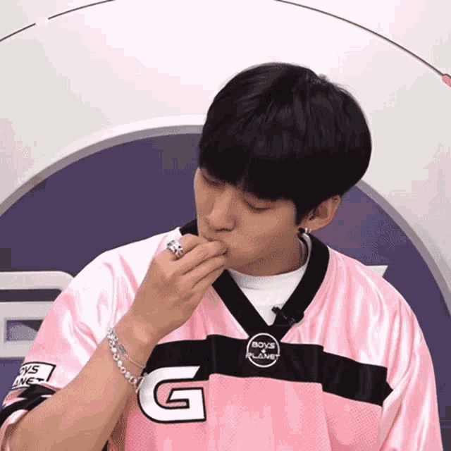 a young man wearing a pink boys planet jersey