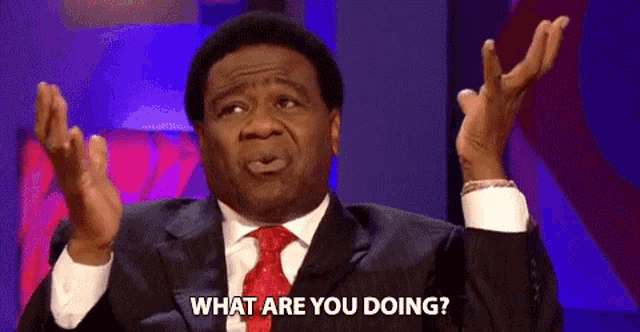 a man in a suit and tie is making a funny face while asking what are you doing .
