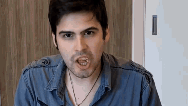 a man in a blue shirt with a necklace around his neck