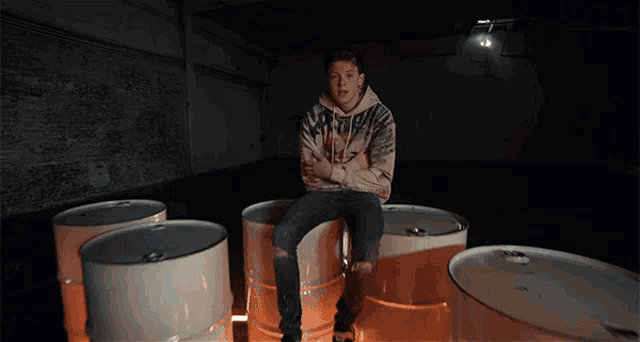 a man sitting on a barrel with his arms crossed