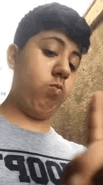 a young man is making a funny face while wearing a gray t-shirt .