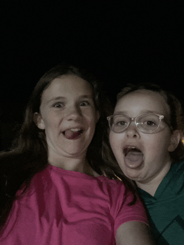 two girls with glasses sticking their tongues out at the camera