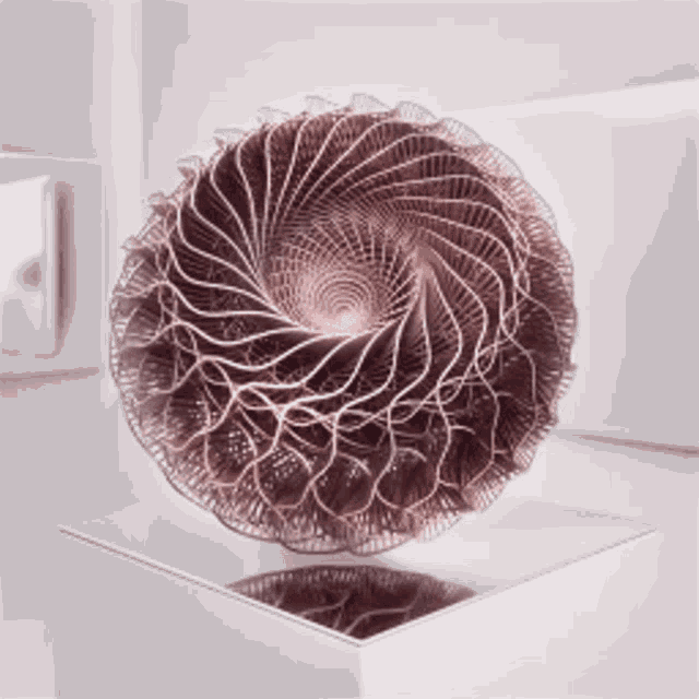 a circular sculpture is sitting on top of a glass pedestal