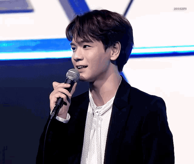 a young man is holding a microphone and smiling