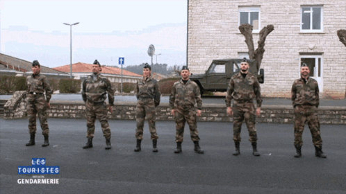 a group of soldiers standing in front of a building with the words les touristes gendarmerie on the bottom