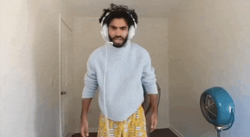 a man wearing headphones is standing in a room next to a fan