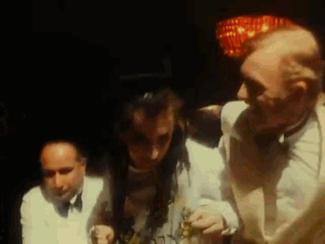 a group of men are standing next to each other in a dark room and talking .