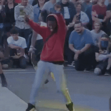 a man in a red hoodie is dancing in front of a crowd of people