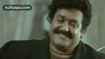 a man with a mustache is making a funny face while sitting on a couch .