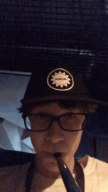 a man wearing glasses and a hat that says arua