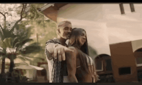a man and a woman are dancing in front of a building in a video .