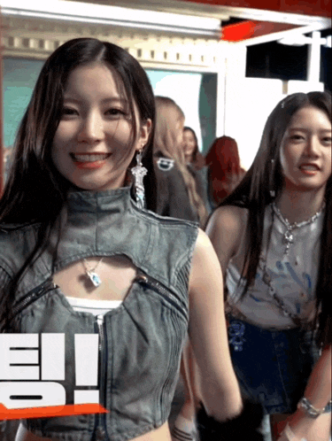 a girl in a denim vest is smiling in front of a sign that says io