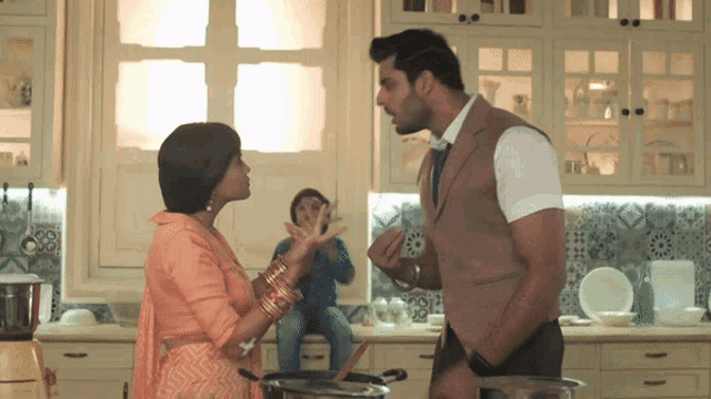 a man and a woman are standing in a kitchen having a conversation