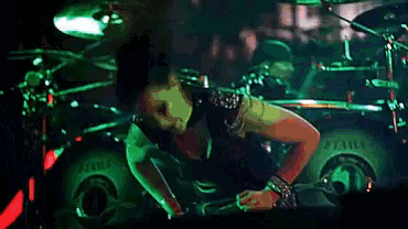 a woman dancing in front of a drum set that says tama
