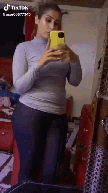 a woman is taking a picture of herself in a mirror with her phone .