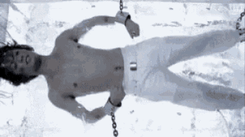 a man is chained to a block of ice without a shirt .