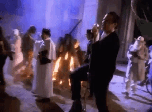 a man in a suit is dancing in a crowd of people in a room .