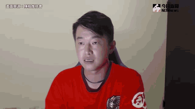 a man in a red shirt is sitting in front of a computer screen