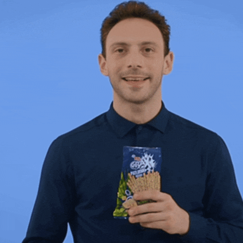 a man in a blue shirt holds a bag of crackers