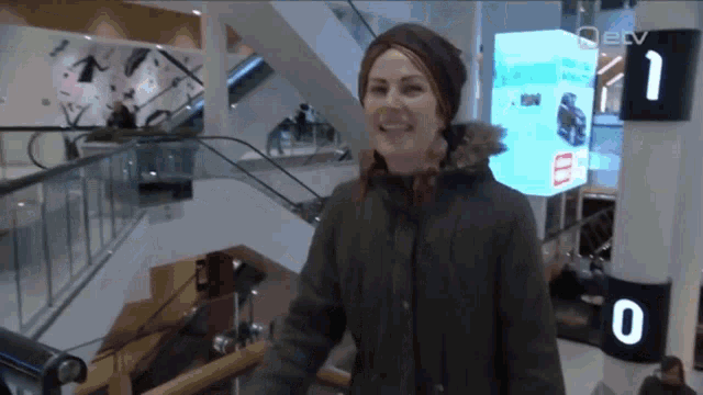 a woman is smiling in front of a sign that says ectv