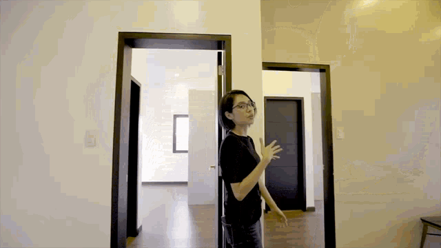 a woman in a black shirt is standing in an empty room between two doors