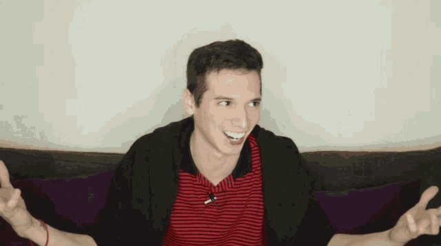 a man wearing a red and black striped shirt is sitting on a couch