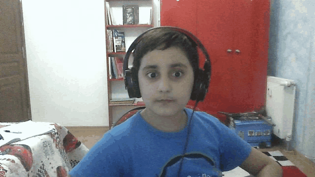 a young boy wearing headphones and a blue shirt with a circle on the front